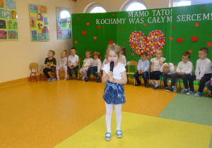 Dziewczynka trzyma w ręku mikrofon, recytuje wiersz.